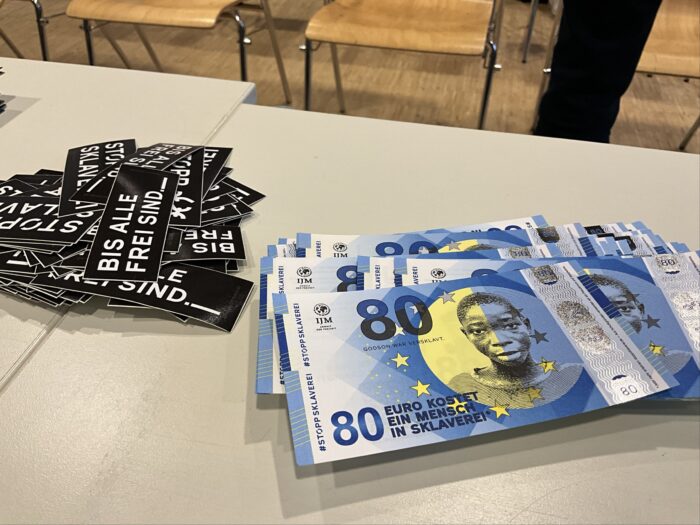 Tisch mit Aufklebern und fiktiven Geldscheinen.